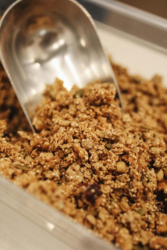 Close-up of crunchy homemade granola being scooped, perfect for a nutritious breakfast.