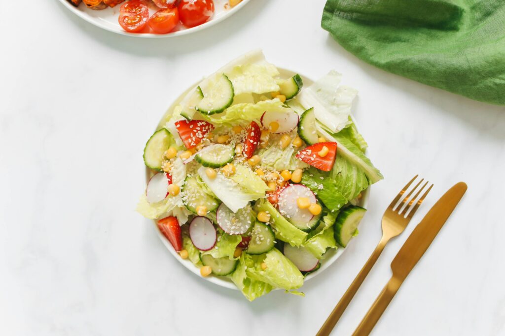 Colorful vegetable salad with lettuce, cucumbers, and radishes on a white plate.
