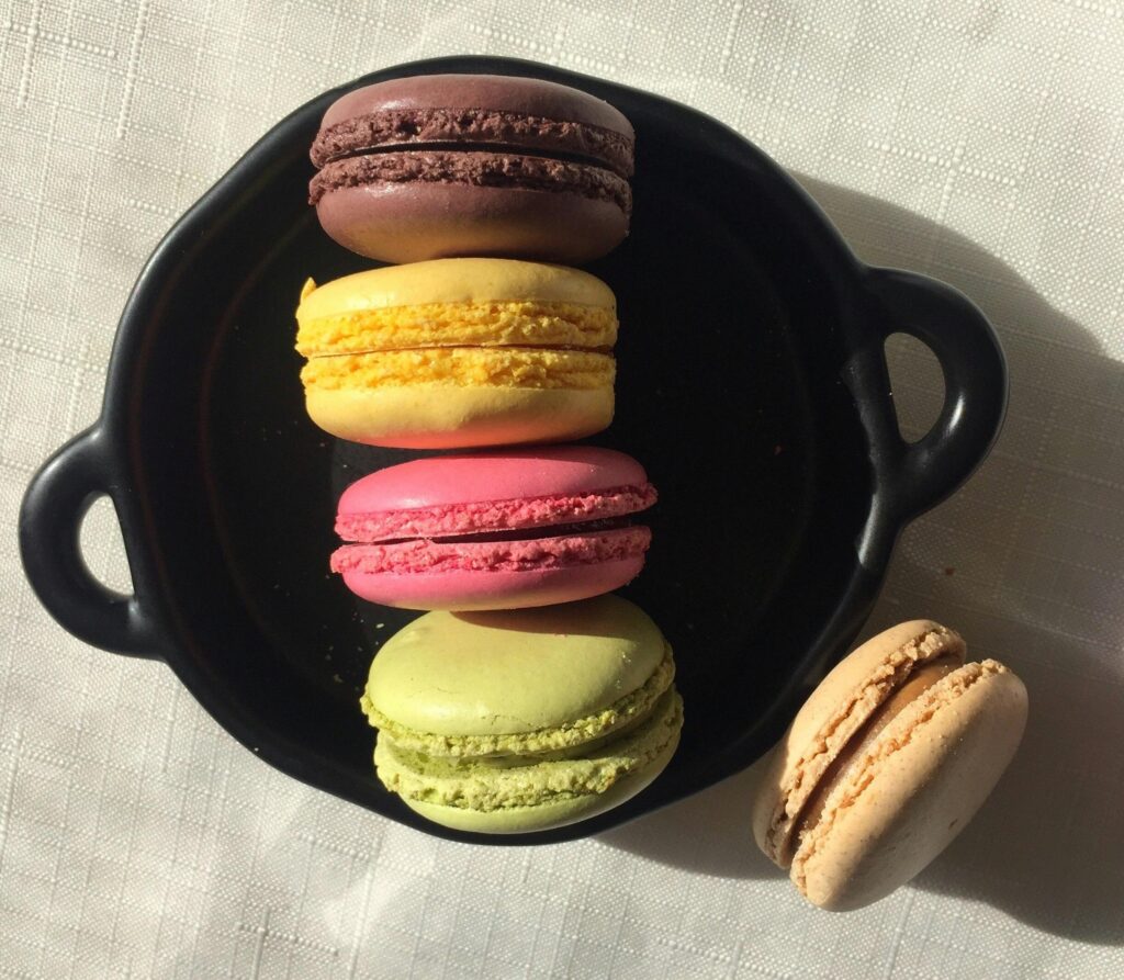 pexels-photo-8397914-8397914 Colorful macarons arranged on a black plate with natural lighting.