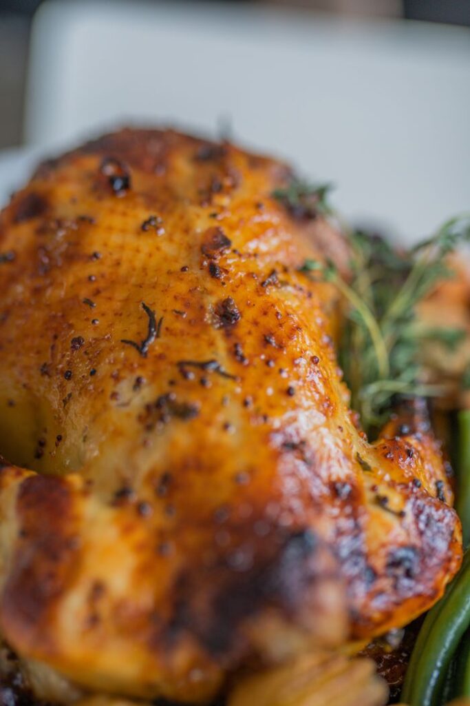 Close-up of a juicy roasted chicken with herbs, perfect for food lovers.