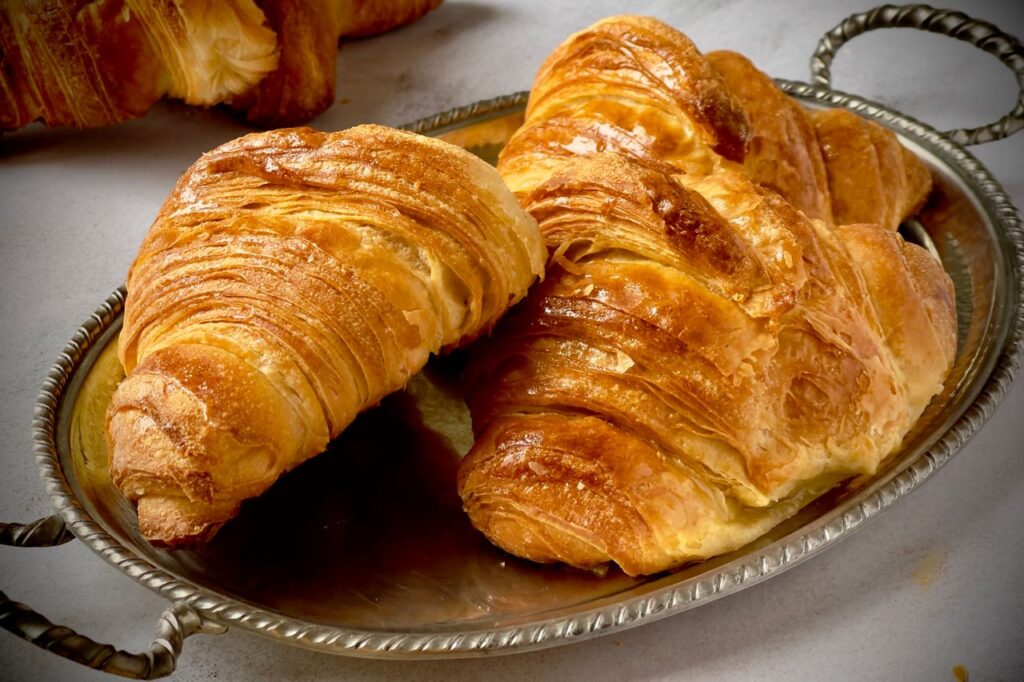 Delicious golden croissants on a silver tray, perfect for breakfast or brunch.