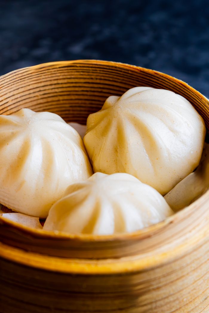 Delicious steamed dumplings in a traditional bamboo basket, perfect for Asian cuisine themes.