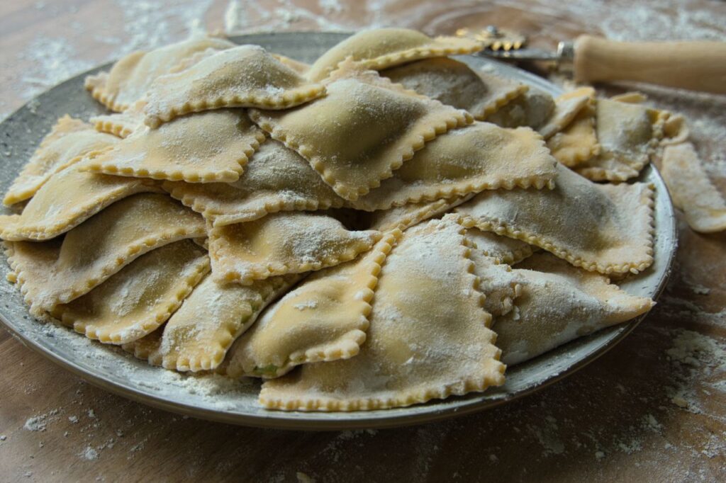 A plate of freshly made ravioli dusted with flour, showcasing traditional Italian cuisine.