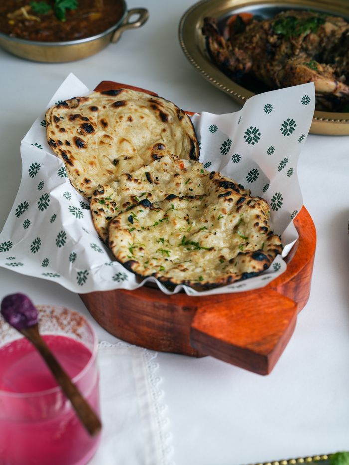 Tantalizing Indian garlic naan served with curry and pink drink.