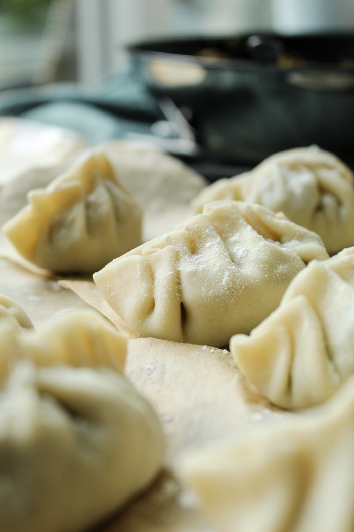Vertical shot of raw handmade dumplings, highlighting their intricate folds.